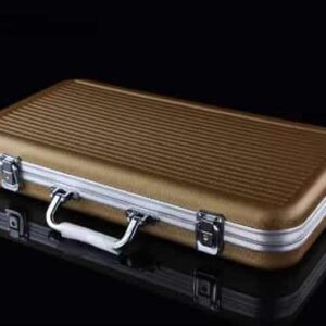 A closed, rectangular, gold - colored aluminum case with a handle and silver clasps, set against a black reflective background.